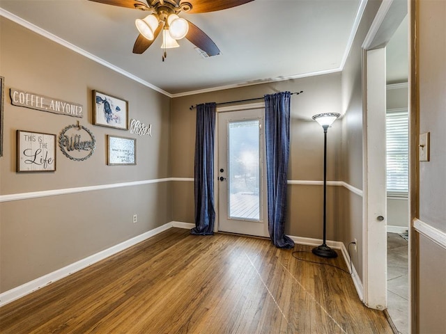 entryway with ornamental molding, ceiling fan, baseboards, and wood finished floors