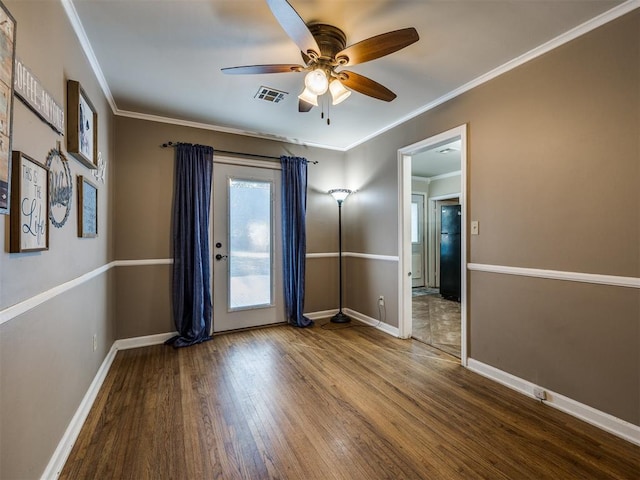 empty room featuring ceiling fan, wood finished floors, visible vents, baseboards, and ornamental molding