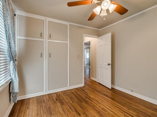 unfurnished bedroom featuring baseboards, wood finished floors, a ceiling fan, and crown molding