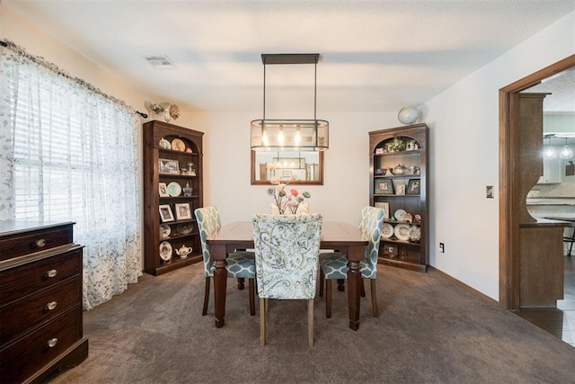 dining room with dark colored carpet, visible vents, and baseboards