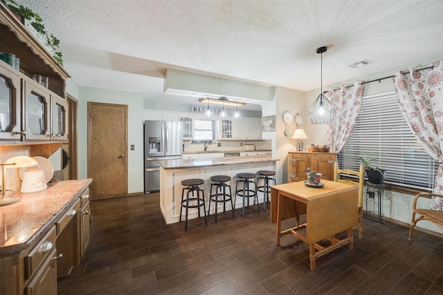 dining area with wood finish floors, visible vents, and a textured ceiling