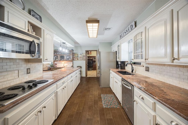 kitchen with appliances with stainless steel finishes, a sink, glass insert cabinets, and white cabinets