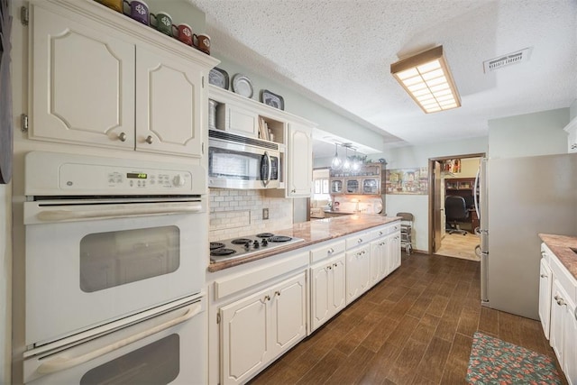 kitchen featuring dark wood-style flooring, light countertops, visible vents, appliances with stainless steel finishes, and white cabinets