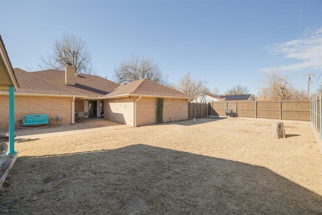 view of yard featuring an attached garage, a patio area, and a fenced backyard