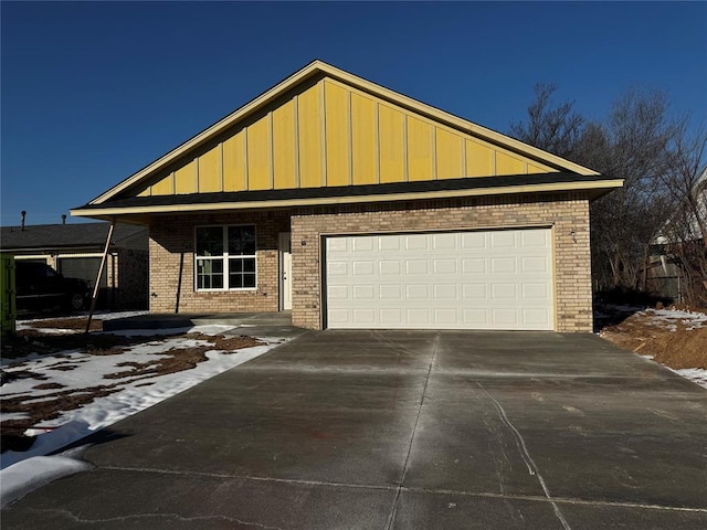 view of front of home featuring driveway, an attached garage, board and batten siding, and brick siding