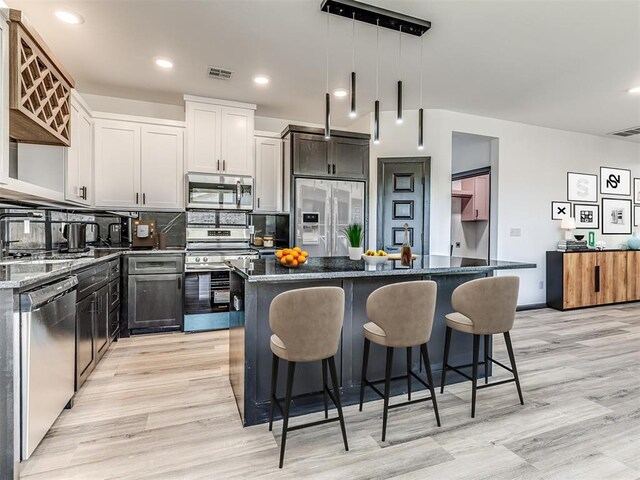 4419 Meadowpark Dr, Midwest City, OK 73110 - kitchen with a kitchen island, light wood finished floors, appliances with stainless steel finishes, and visible vents