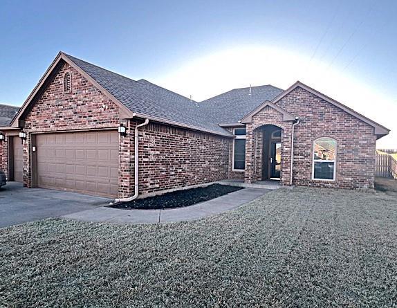 single story home with driveway, brick siding, an attached garage, and a shingled roof