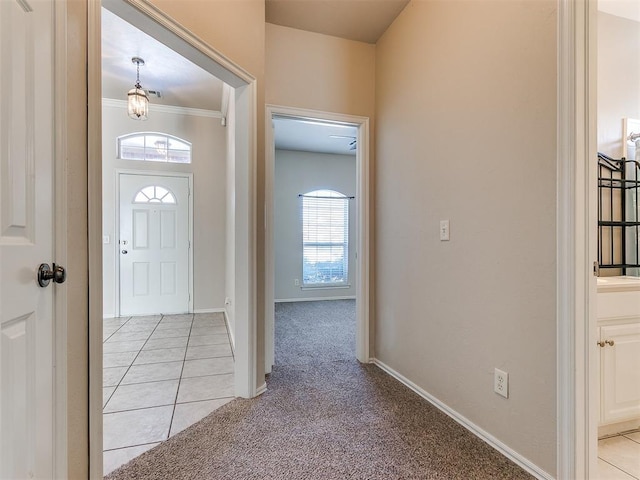 foyer entrance with light carpet, ornamental molding, light tile patterned flooring, and baseboards