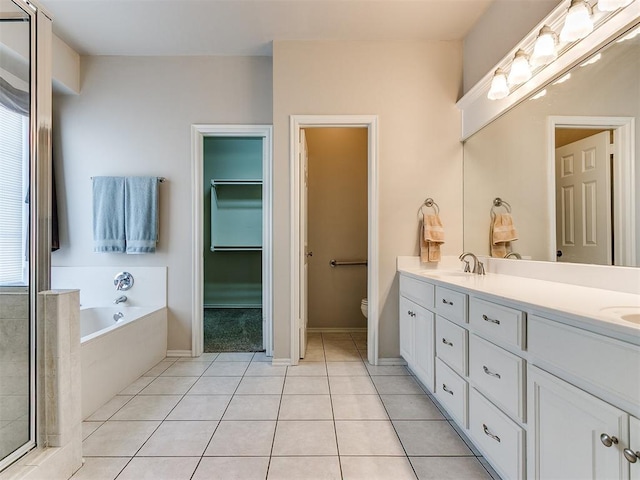 bathroom with a garden tub, double vanity, a sink, and tile patterned floors