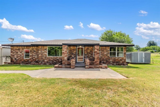 back of house featuring a patio area, a yard, a storage shed, and brick siding