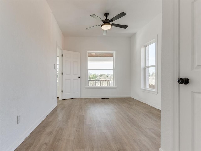 unfurnished room with ceiling fan, visible vents, light wood-style flooring, and baseboards