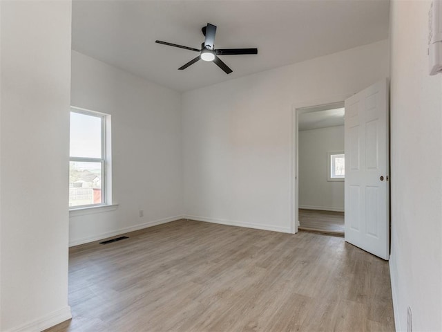 spare room with a wealth of natural light, visible vents, light wood-style flooring, and baseboards