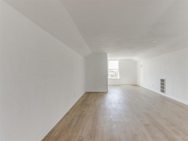 additional living space featuring lofted ceiling, visible vents, and light wood-style flooring