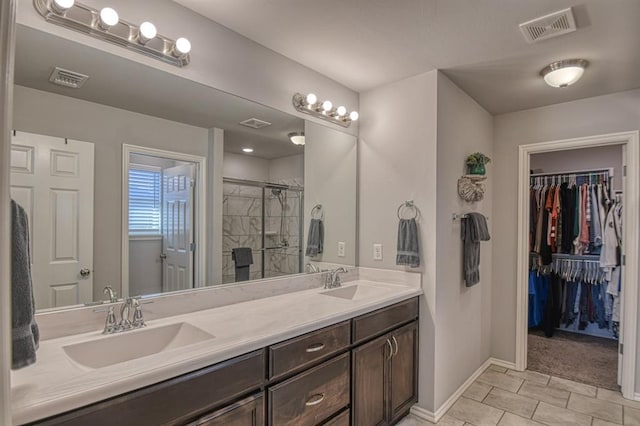 bathroom with double vanity, a shower stall, visible vents, and a sink