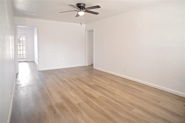 spare room with ceiling fan, light wood-style flooring, and baseboards