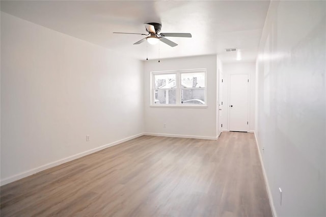 empty room with a ceiling fan, light wood-type flooring, visible vents, and baseboards