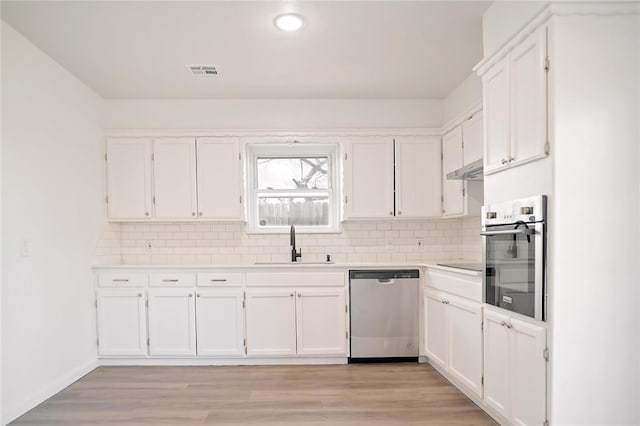 kitchen featuring light wood finished floors, visible vents, appliances with stainless steel finishes, white cabinetry, and a sink