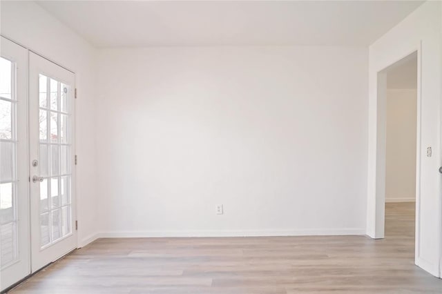 empty room featuring light wood finished floors, french doors, and baseboards