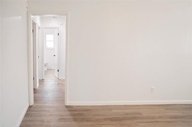 hall with light wood-type flooring and baseboards