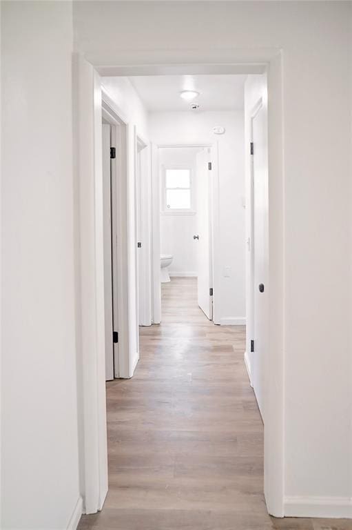 corridor with light wood finished floors and baseboards