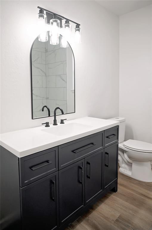 bathroom with toilet, wood finished floors, and vanity