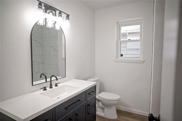 full bath featuring toilet, wood finished floors, vanity, and baseboards