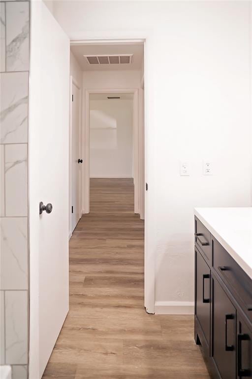 hall featuring light wood finished floors, visible vents, and baseboards