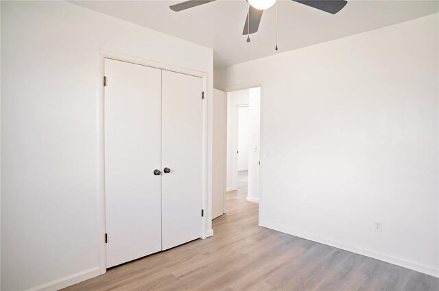 unfurnished bedroom featuring ceiling fan, a closet, baseboards, and light wood-style floors