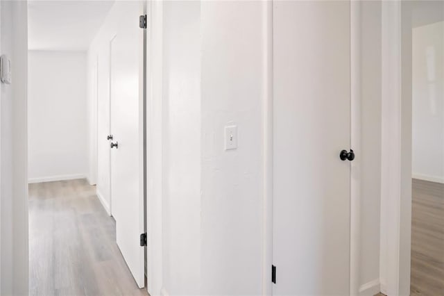 hall featuring baseboards and light wood finished floors