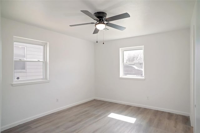 spare room with wood finished floors, a ceiling fan, and baseboards