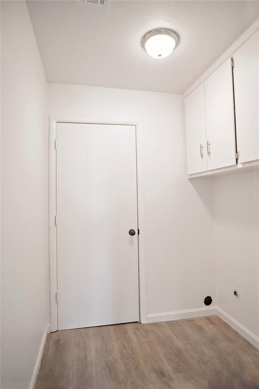 washroom with cabinet space, hookup for an electric dryer, baseboards, and wood finished floors