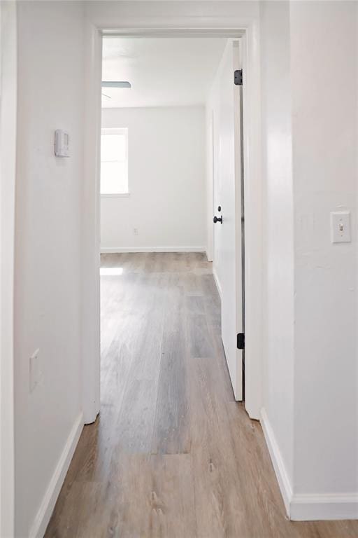 hallway with light wood-type flooring and baseboards