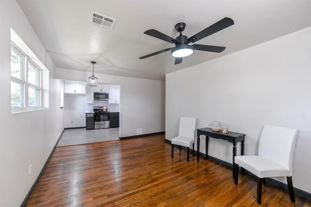 living area featuring visible vents, dark wood finished floors, baseboards, and ceiling fan