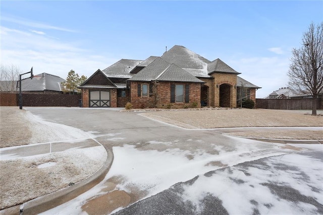 view of front of property featuring a garage, a shingled roof, aphalt driveway, fence, and brick siding