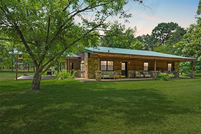 back of house featuring stone siding and a lawn