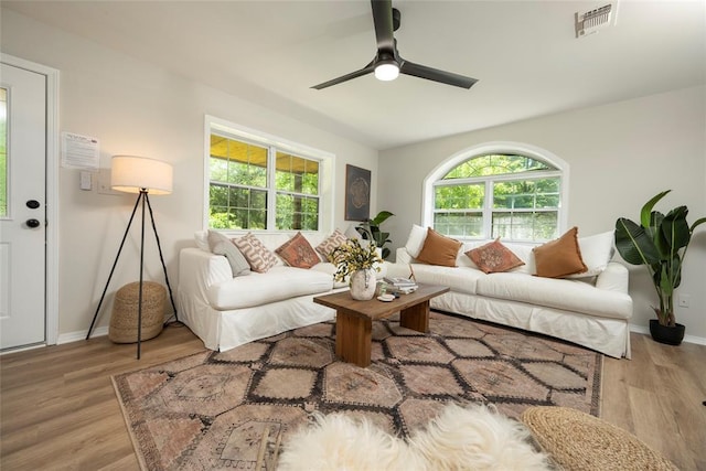 living area with baseboards, wood finished floors, visible vents, and a ceiling fan