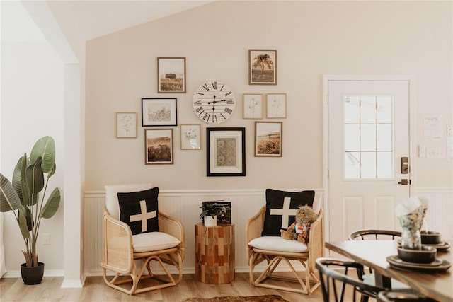 living area with lofted ceiling, wood finished floors, and wainscoting