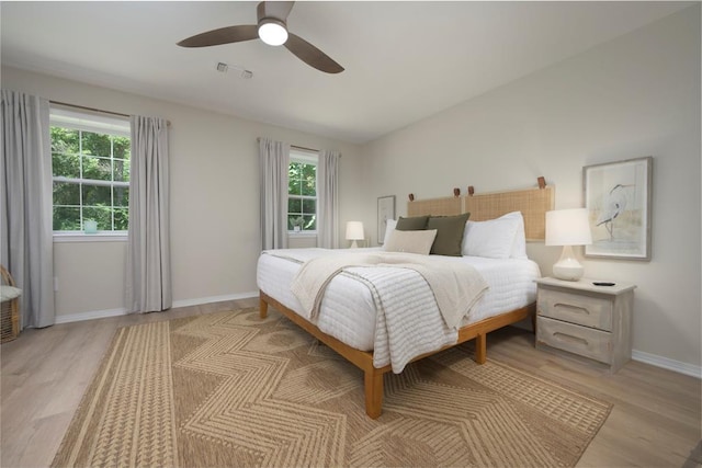 bedroom with light wood-style flooring, visible vents, ceiling fan, and baseboards