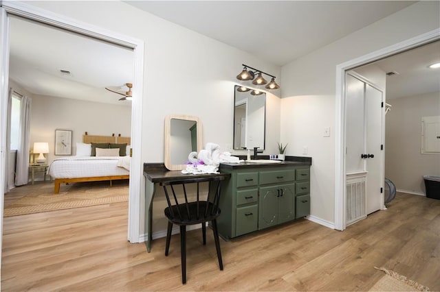 ensuite bathroom featuring visible vents, vanity, ensuite bath, wood finished floors, and baseboards