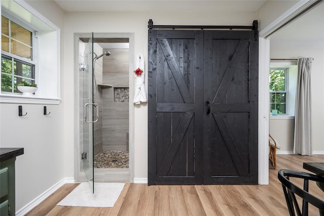 full bathroom featuring a stall shower, wood finished floors, and baseboards