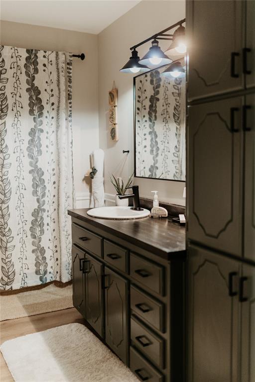 full bathroom with curtained shower, wood finished floors, and vanity