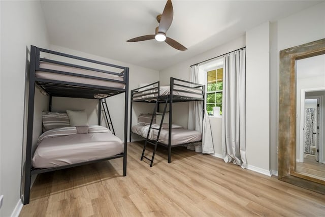 bedroom with light wood finished floors, baseboards, and a ceiling fan