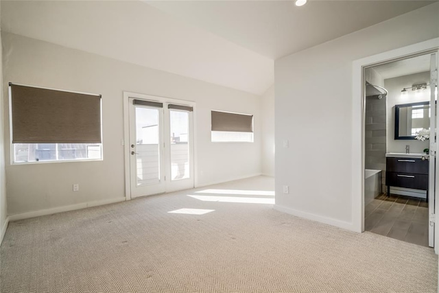 empty room featuring light colored carpet, a sink, and baseboards