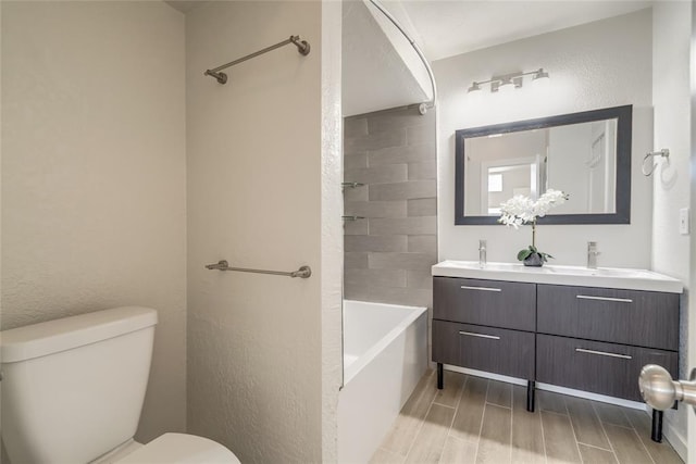 bathroom with shower / bathtub combination, a textured wall, toilet, wood tiled floor, and double vanity