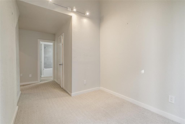 unfurnished room with baseboards and light colored carpet