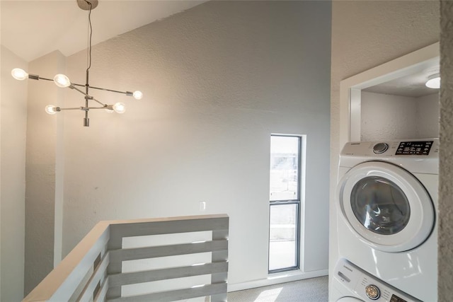 washroom featuring laundry area, stacked washing maching and dryer, and an inviting chandelier