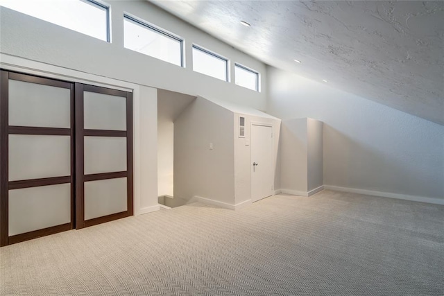 additional living space with a high ceiling, baseboards, and light colored carpet