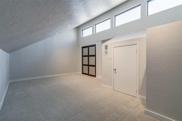 bonus room featuring a textured ceiling, high vaulted ceiling, a textured wall, light carpet, and baseboards