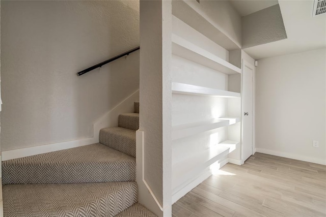 staircase featuring visible vents, baseboards, and wood finished floors