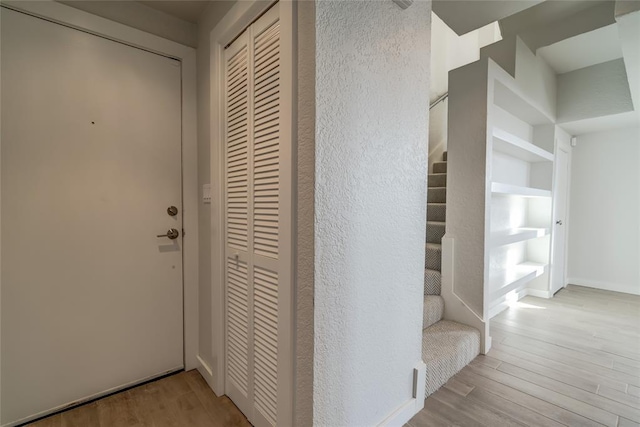 interior space featuring light wood finished floors, baseboards, and stairway